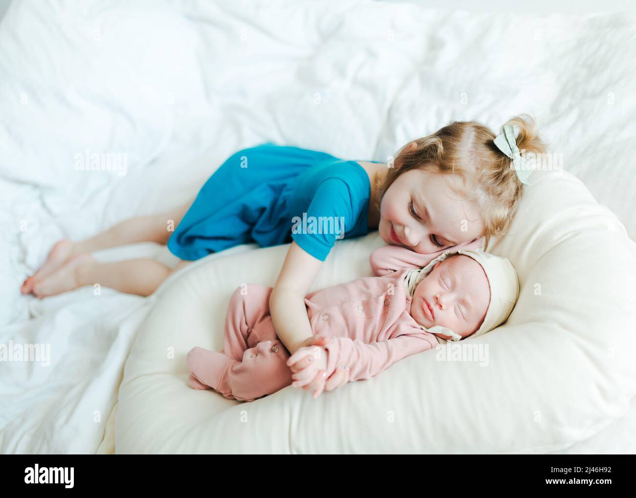 nouveau-né bébé fille dormant sur un lit blanc avec sa sœur aînée Banque D'Images