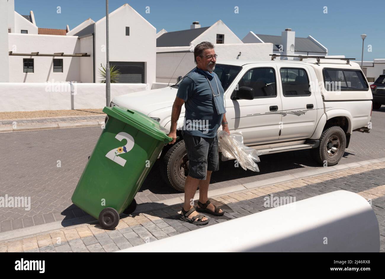 Côte ouest, Afrique du Sud. 2022. Résident déplaçant un bac de recyclage vert vide de la route vers sa propriété. Banque D'Images