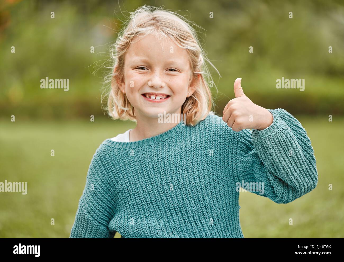 C'est très bien. Photo d'une adorable petite fille montrant les pouces vers le haut tout en se tenant à l'extérieur. Banque D'Images