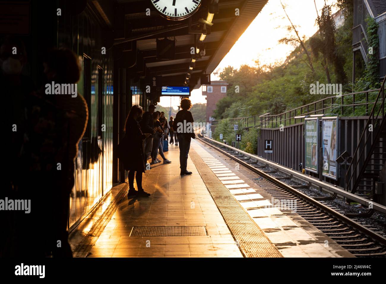 Les gens attendent sur une plate-forme pour le prochain train. Voyager avec le S-Bahn en ville. Heure de pointe à Berlin. La lumière du soleil brille. Banque D'Images