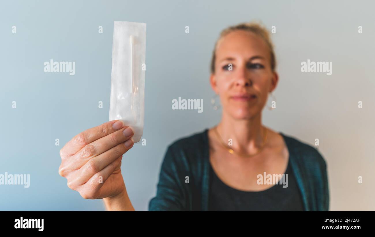 La femme maintient le écouvillon de test nasal PCR sras Covid 19 non ouvert sur la caméra Banque D'Images