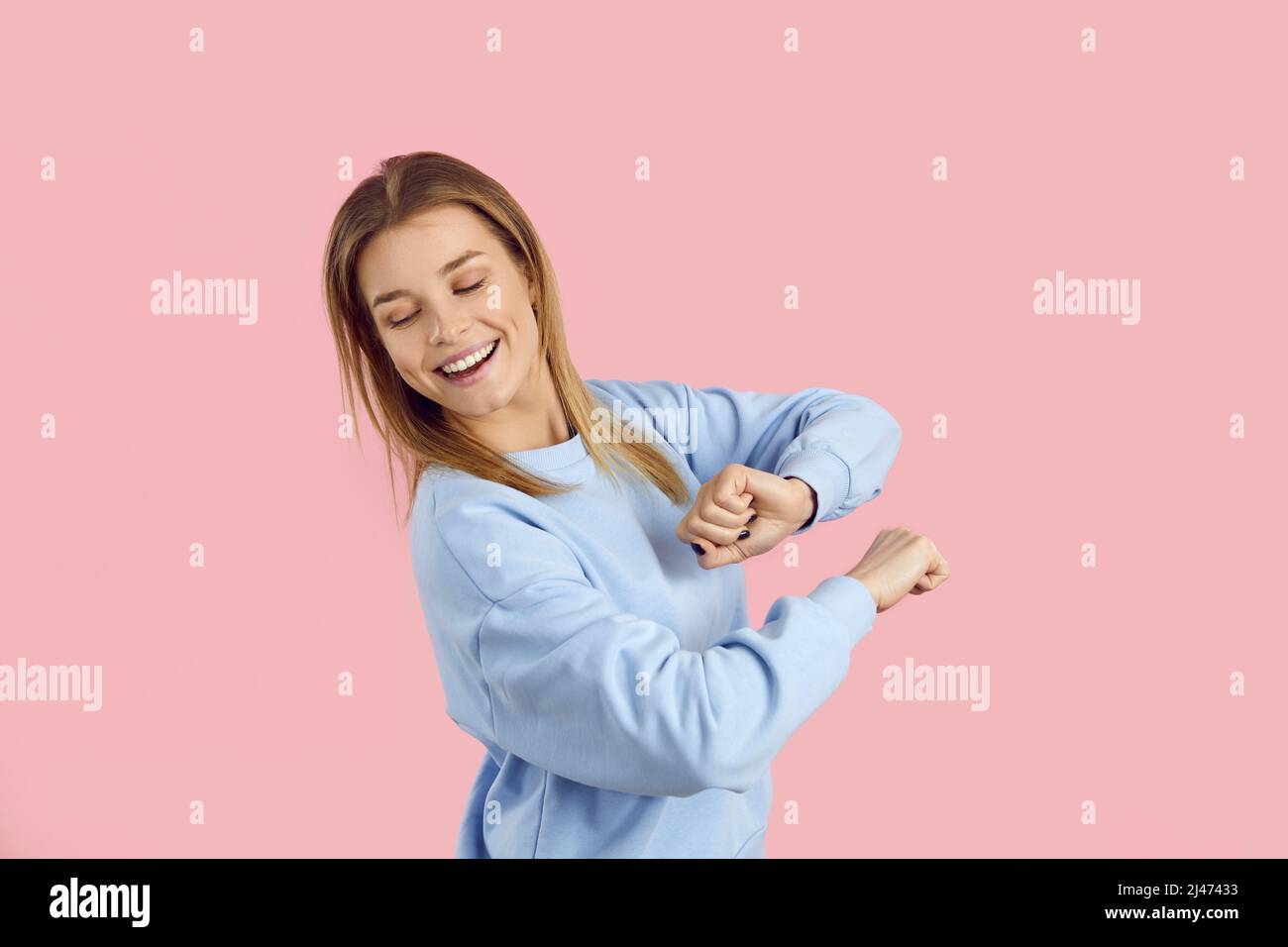Portrait d'une jeune fille heureuse dansant à la musique moderne sur fond rose studio Banque D'Images