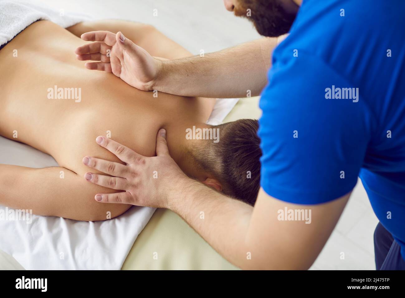 Massagiste professionnel au salon de spa ou à la salle de massage faisant un massage du dos réparateur pour les jeunes hommes Banque D'Images