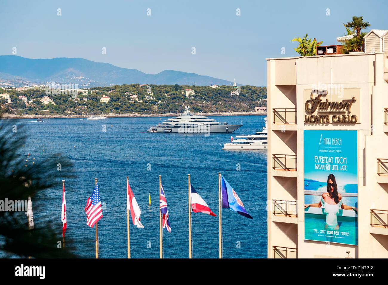 Monaco, Monte Carlo, 21 août 2017: L'hôtel Fairmont, drapeaux de différents pays sur les mâts de drapeau, méga yachts sur fond, la mer Méditerranée et Banque D'Images