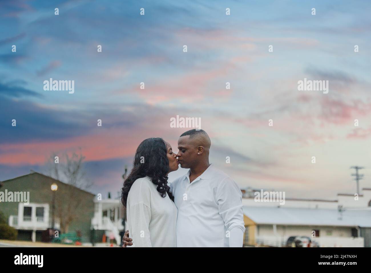 Un couple mignon dans la trentaine qui embrasse au coucher du soleil Banque D'Images