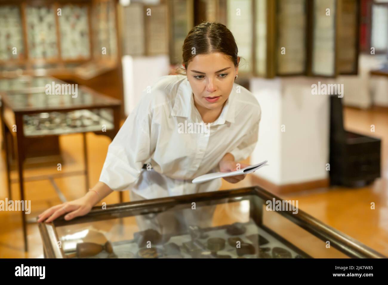 Jeune femme avec brochure d'information visitant le musée Banque D'Images