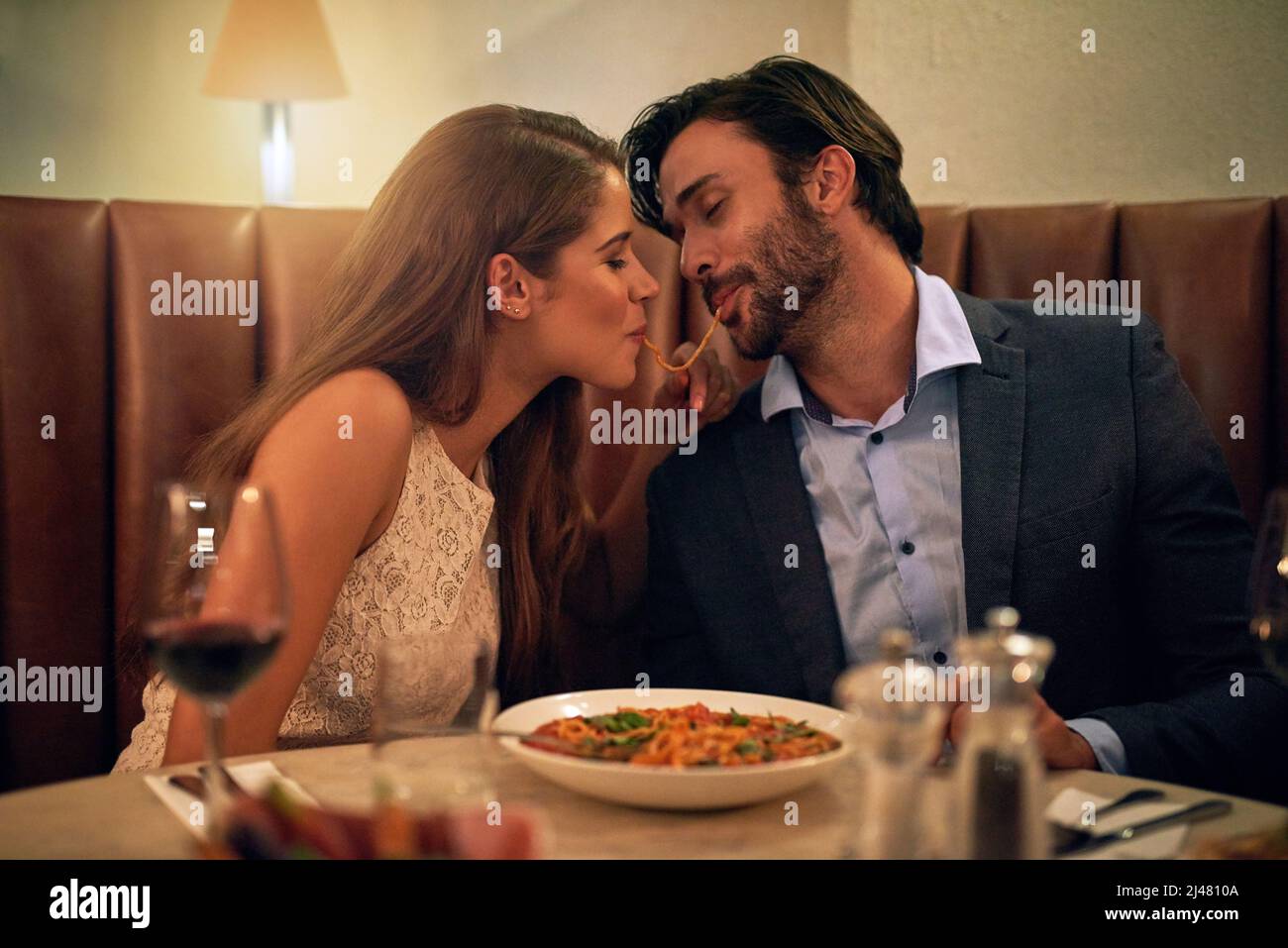 Les morsures d'amour. Photo d'un jeune couple partageant des spaghetti lors d'un dîner romantique dans un restaurant. Banque D'Images