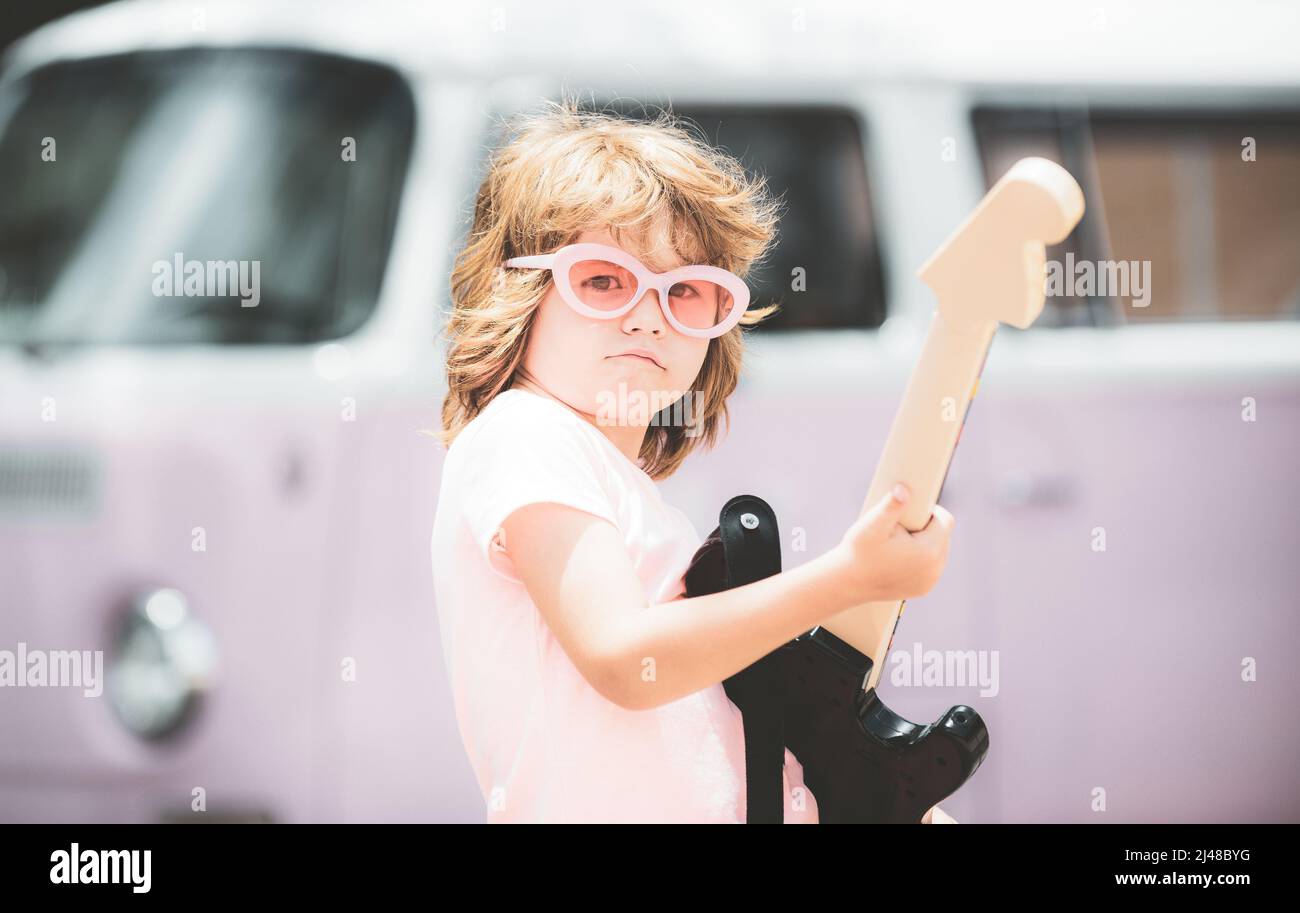 Enfant musicien avec une guitare. Joyeux mignon enfant improvisant. Happy Kid aime la musique sur fond rose coloré. Banque D'Images