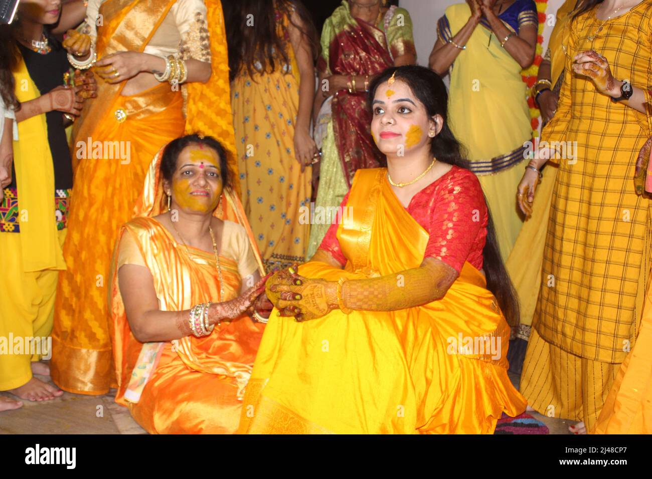 Mariée hindoue indienne avec pâte curcuma appliquée sur son visage en s'amusant avec sa famille et ses amis. Concept de mariage indien Banque D'Images