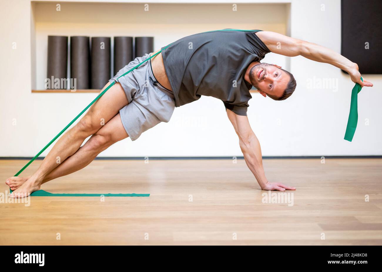 Ajuster musclé homme faisant un exercice de bande de résistance dans une longueur d'étirement de côté pour renforcer et tonifier ses muscles de noyau Banque D'Images