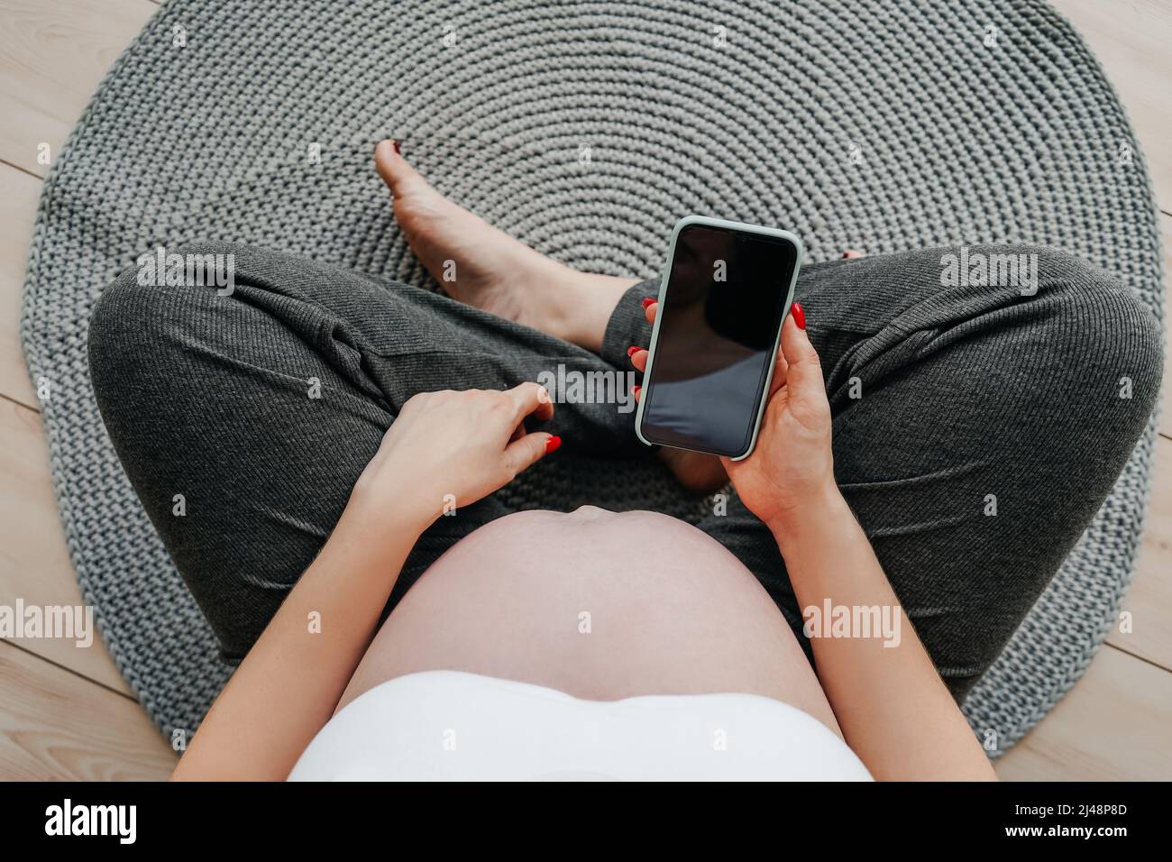 Femme enceinte avec un téléphone dans ses mains, vue du dessus. Concept d'achat en ligne. Banque D'Images