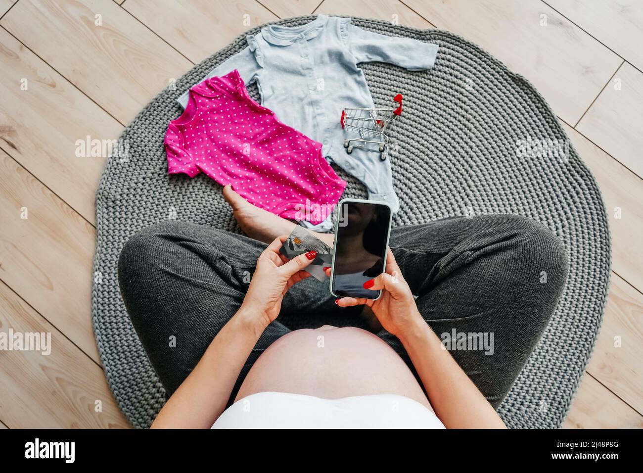 Femme enceinte avec un téléphone dans ses mains, vue du dessus. Concept d'achat en ligne. Banque D'Images