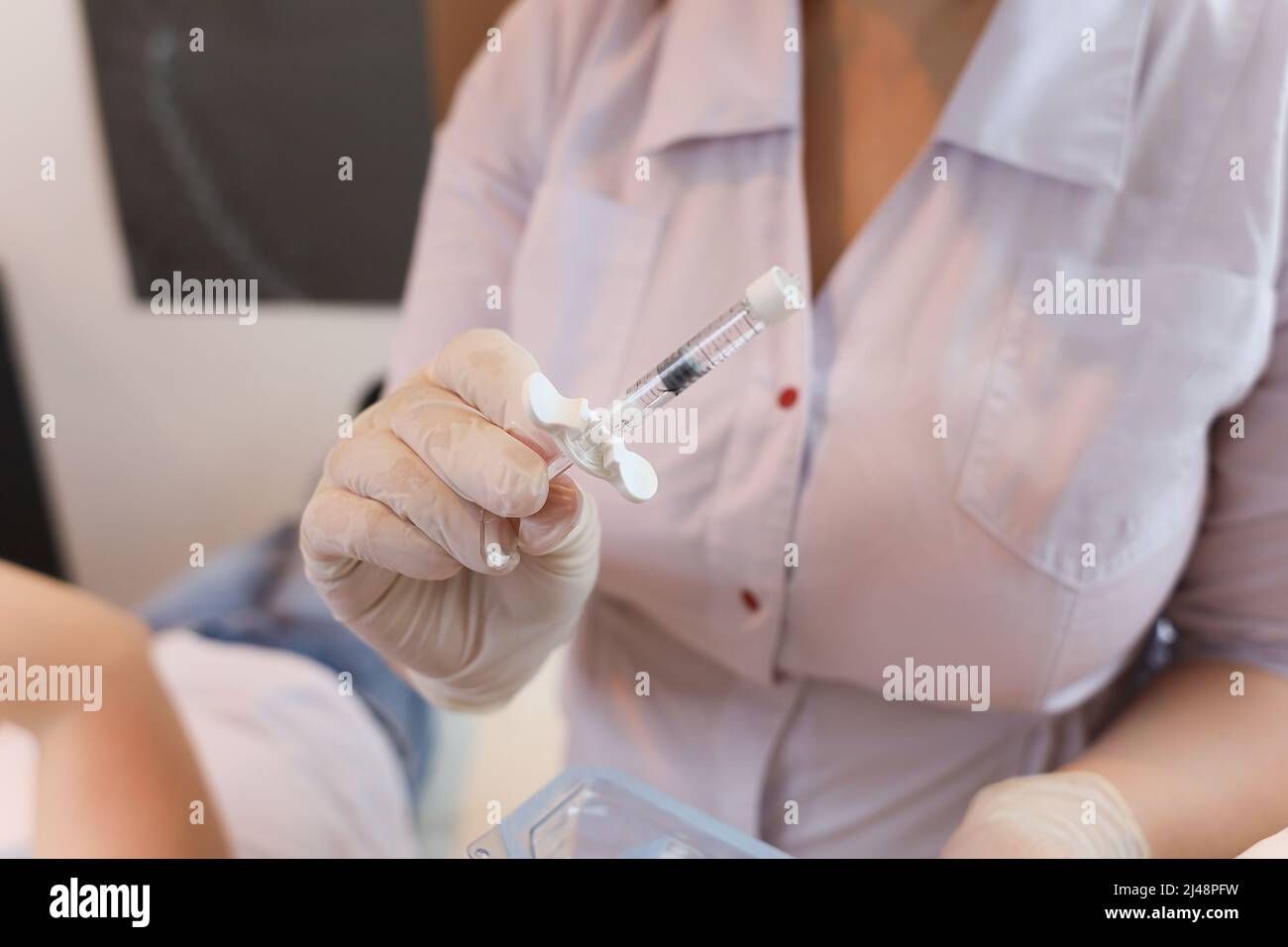 Le cosmétologue tient dans ses mains un mastic pour l'introduction d'injections d'acide hyaluronique dans les lèvres Banque D'Images