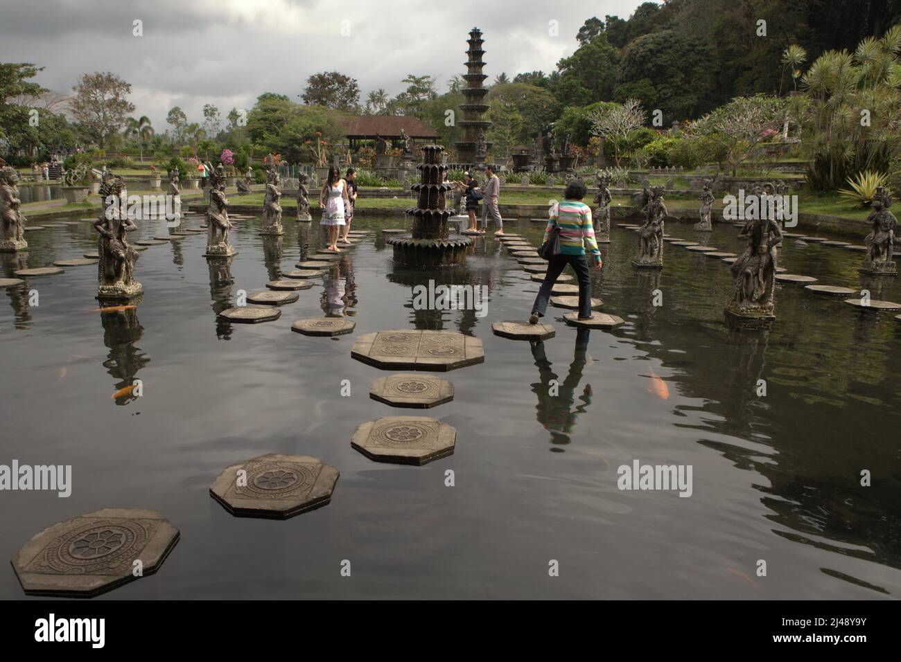 Les visiteurs marchent sur des traces de pierre au palais aquatique Tirta Gangga à Karangasem, Bali. Construit sur la base d'une croyance que l'eau est sainte, le Gangga de Tirta (tirta signifie « l'eau sainte »; Gangga fait référence au Gange en Inde) était un ancien palais royal du royaume de Karangasem. Banque D'Images