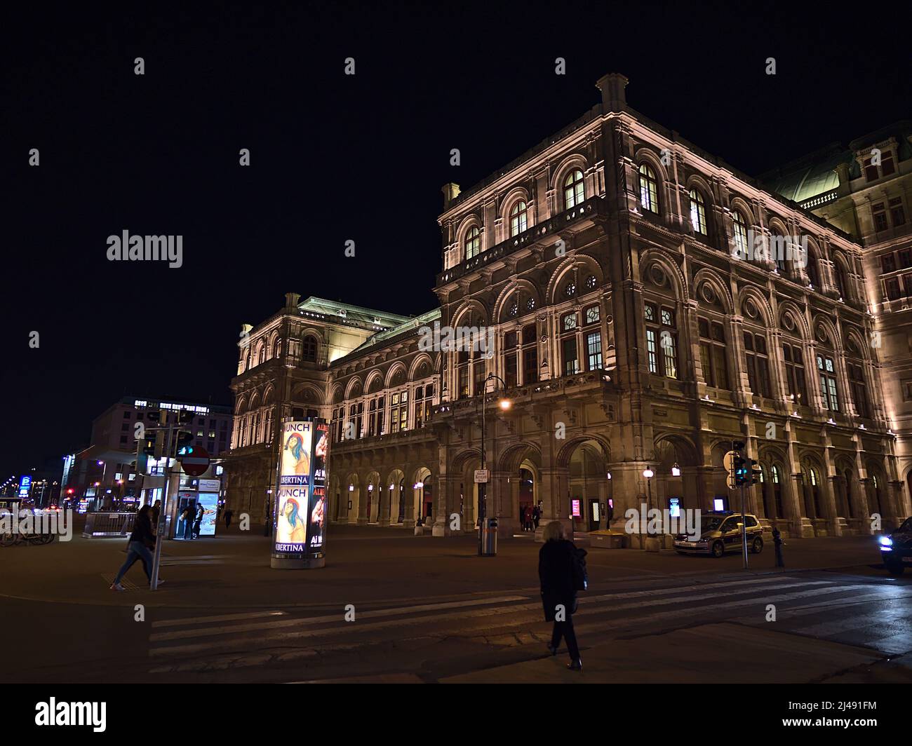 Vue nocturne du célèbre opéra national de Vienne en Autriche avec façade éclairée et personnes passant dans le centre-ville historique. Banque D'Images