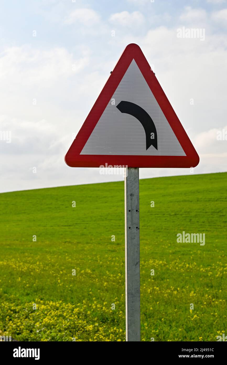 Panneau de signalisation - danger courbe dangereuse - champ de céréales vert Banque D'Images