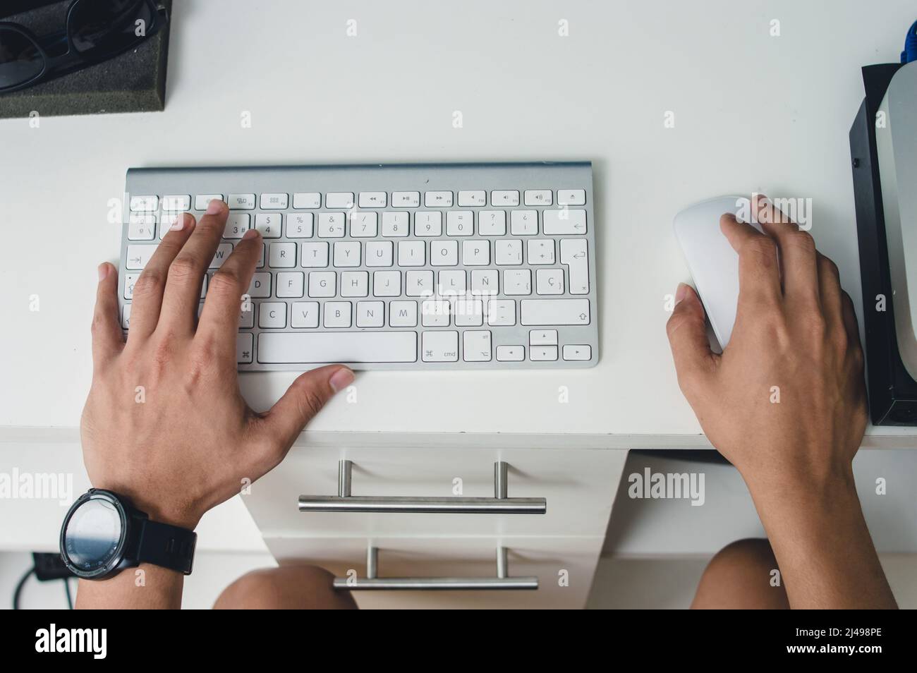 vue de dessus les mains de sexe masculin caucasien en utilisant un clavier d'ordinateur et une souris sur une table blanche, en tapant et en travaillant à domicile, espace de copie. Banque D'Images