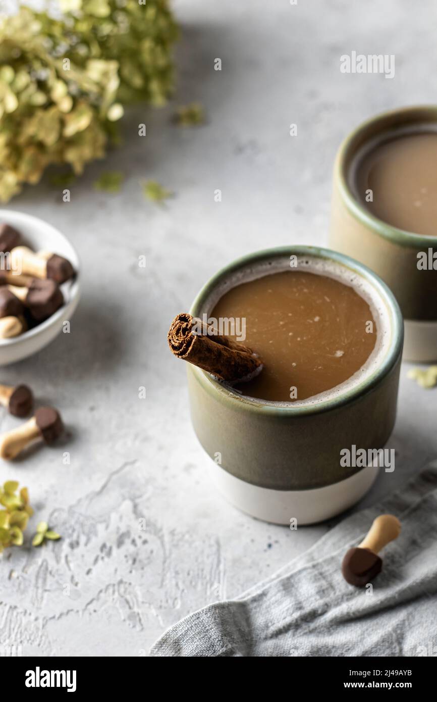 Tasses en céramique avec cappuccino au café et bâton de cannelle à l'intérieur, biscuits, serviette et fleurs sur fond texturé. Le petit déjeuner italien est encore vivant Banque D'Images
