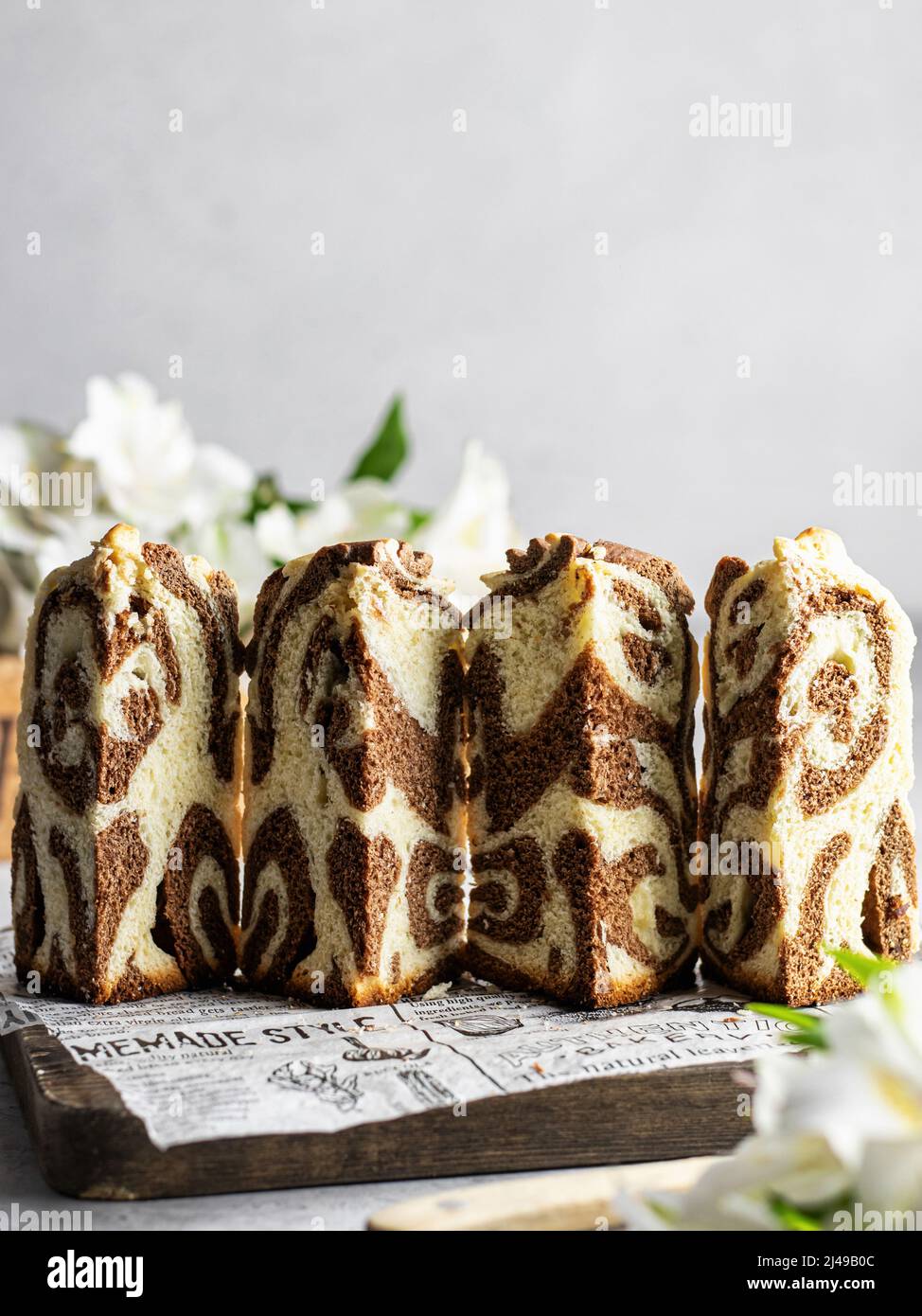 Gâteau de Pâques taillé kraffin arrosé de sucre en poudre sur panneau de bois . Gros plan sur un gâteau fait maison en deux couleurs. Cruffin. Orientation Vertica Banque D'Images