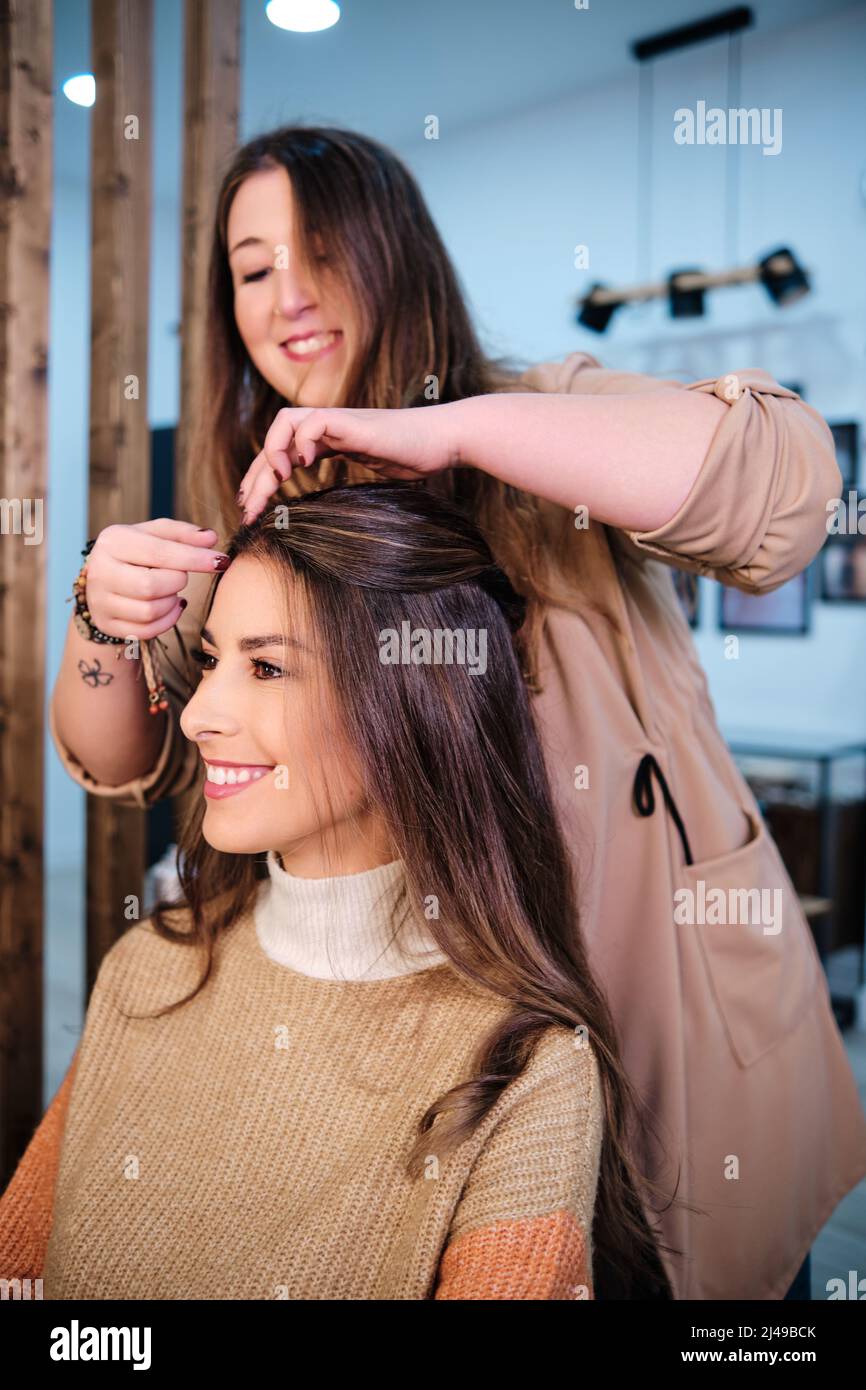 Styliste faisant une coiffure à une femme cliente dans le salon de coiffure. Banque D'Images
