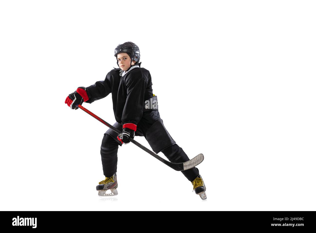 Concentration. Enfant, joueur de hockey avec bâton sur cour de glace et fond blanc. Banque D'Images
