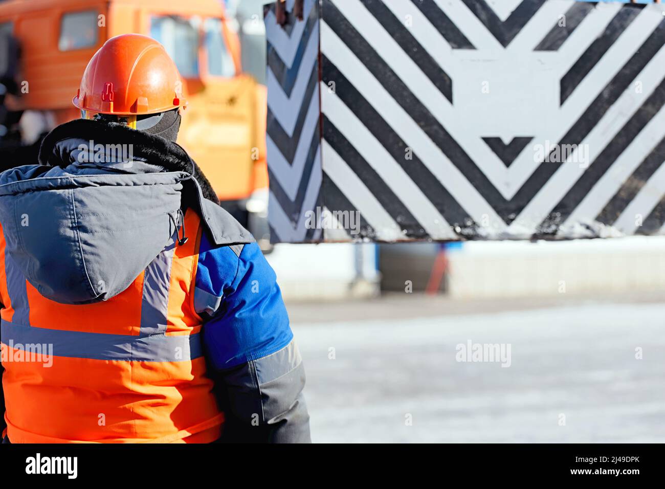 Le déflecteur de sécurité professionnel en casque de construction à l'usine décharge la cargaison. Formation au démarrage. Le travailleur en vêtements chauds d'hiver supervise le déchargement à l'extérieur le jour d'hiver. Banque D'Images