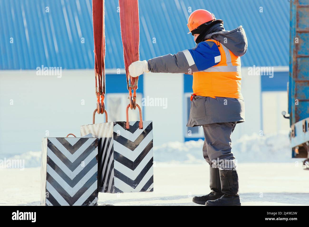 Le déflecteur de sécurité professionnel en casque de construction à l'usine décharge la cargaison. Formation au démarrage. Le travailleur en vêtements chauds d'hiver supervise le déchargement à l'extérieur le jour d'hiver. Banque D'Images