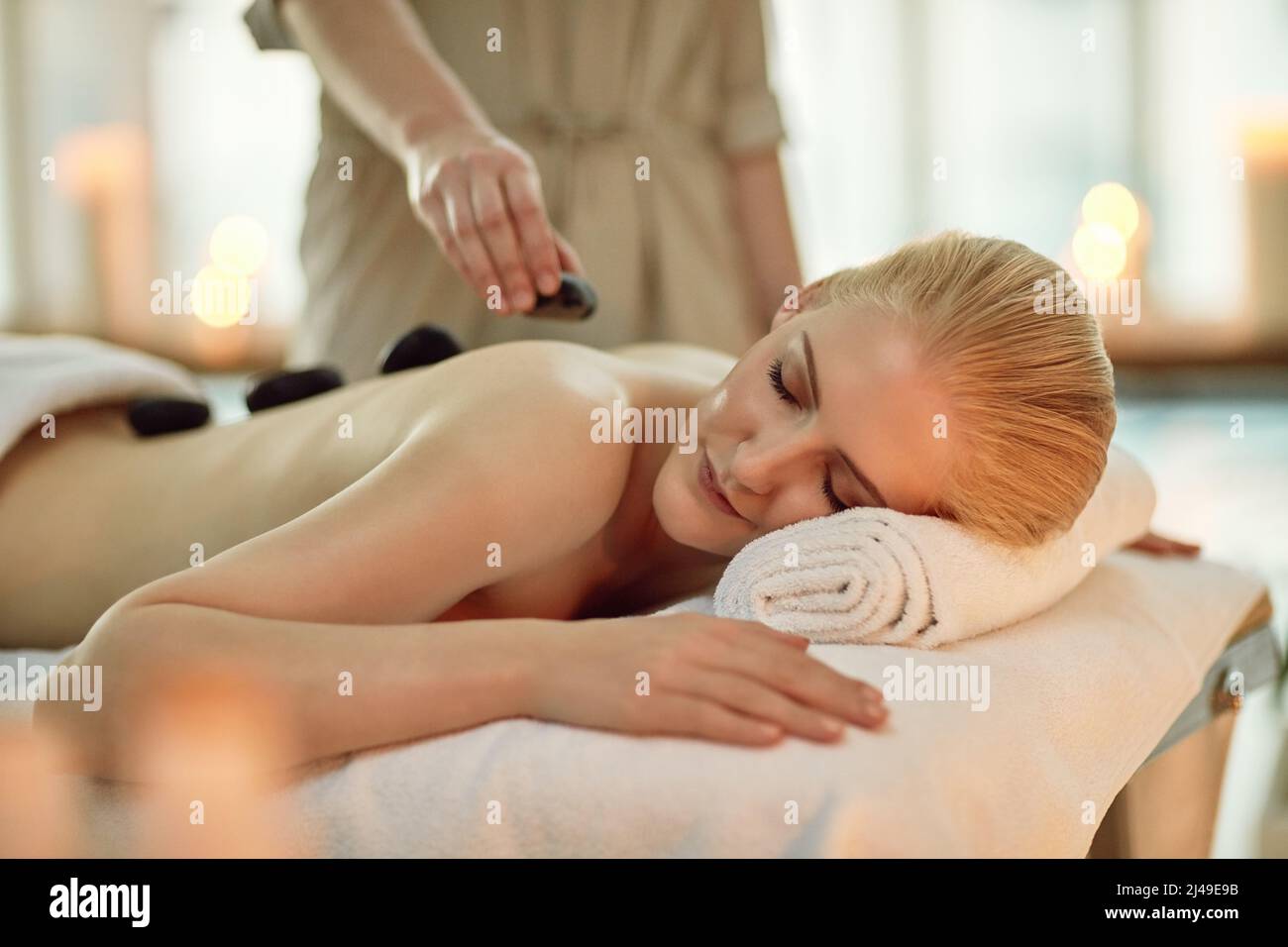 C'est là où le temps est encore. Petit cliché d'une jeune femme bénéficiant d'un massage aux pierres chaudes dans un spa. Banque D'Images