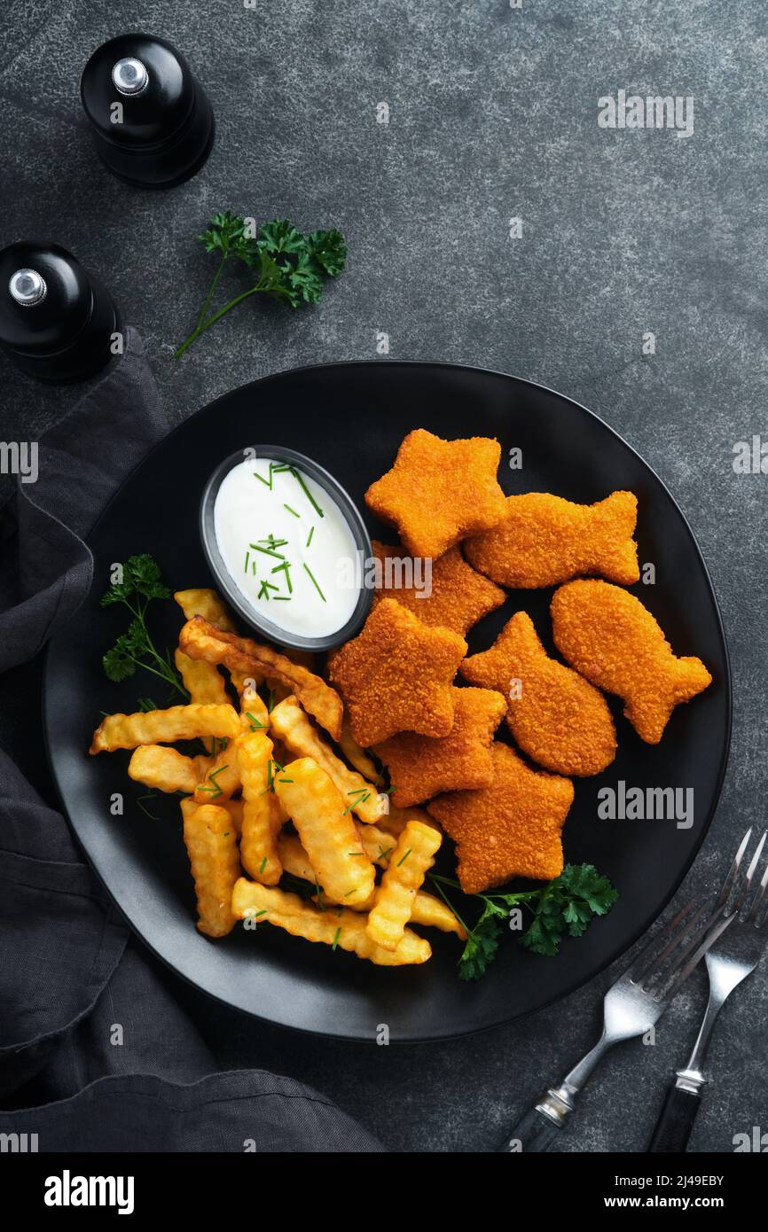 Fish Chips, restauration rapide britannique. Bâtonnets de poisson avec frites sur plaque noire sur fond de table noire. Cuisine traditionnelle britannique authentique ou Banque D'Images