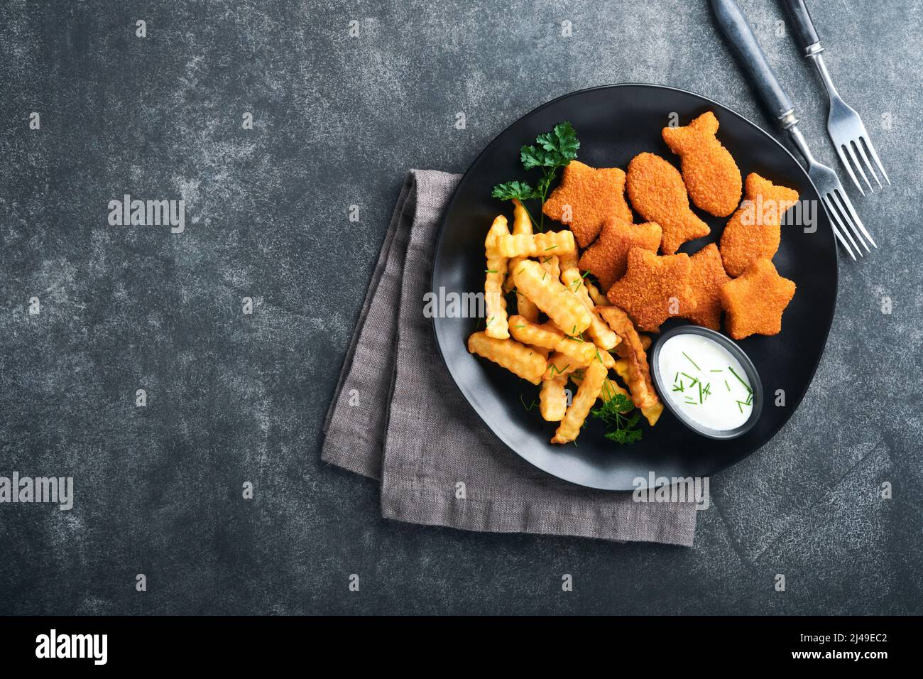 Fish Chips, restauration rapide britannique. Bâtonnets de poisson avec frites sur plaque noire sur fond de table noire. Cuisine traditionnelle britannique authentique ou Banque D'Images