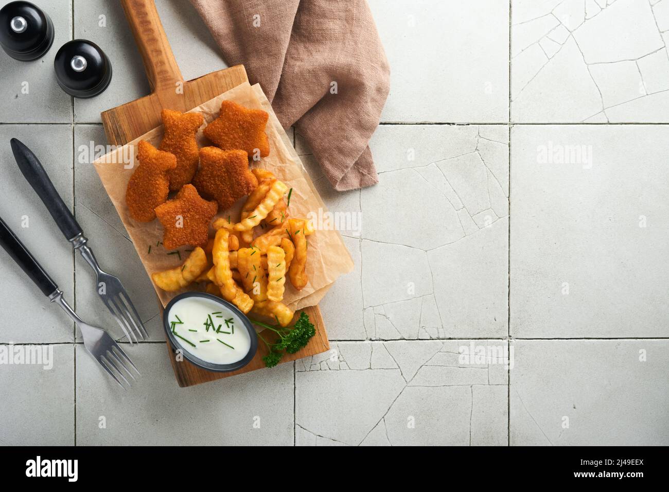 Fish Chips, restauration rapide britannique. Les bâtonnets de poisson aux frites sont fixés sur un panneau rustique, sur un fond de table de comptoir en carreaux gris craquelés. Tradition Banque D'Images