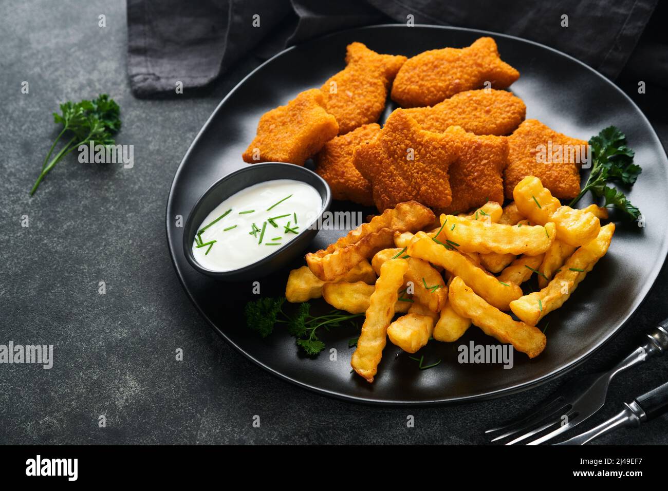 Fish Chips, restauration rapide britannique. Bâtonnets de poisson avec frites sur plaque noire sur fond de table noire. Cuisine traditionnelle britannique authentique ou Banque D'Images