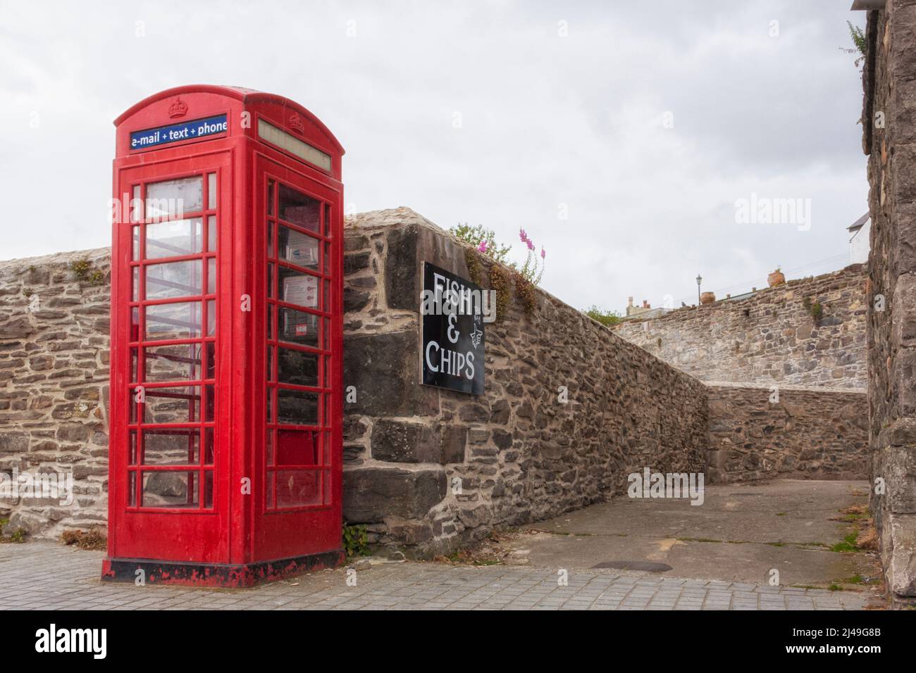 Grands clichés de Grande-Bretagne : cabine téléphonique rouge, murs du château, panneau Fish and Chips, ciel terne. Banque D'Images