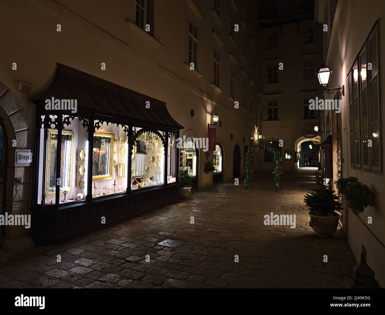 Perspective décroissante d'allée étroite avec les fenêtres éclairées d'un marchand d'antiquités dans le centre historique de Vienne, en Autriche de nuit. Banque D'Images
