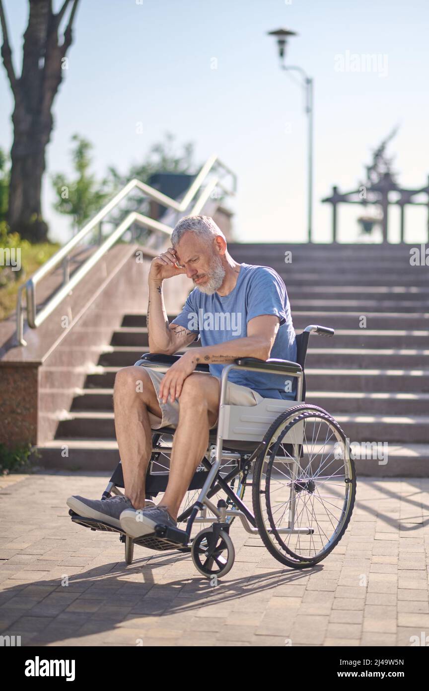 Un homme handicapé dans une chaise roulante à l'extérieur qui a l'air  attentif Photo Stock - Alamy