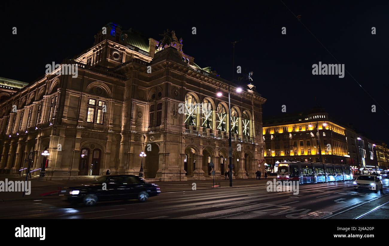 Vue de face de l'entrée principale du célèbre Opéra national de Vienne, Autriche, dans le centre-ville historique avec façade en pierre éclairée. Mouvement flou. Banque D'Images