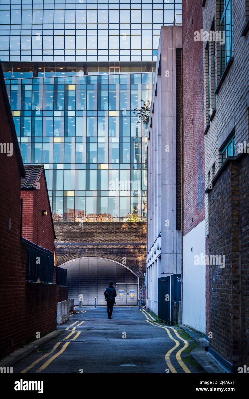 Rue dans une ancienne zone industrielle avec une ancienne arche de brique et un bâtiment moderne de bureau en verre au-delà, London Borough of Southwark, Londres, Angleterre, Royaume-Uni Banque D'Images