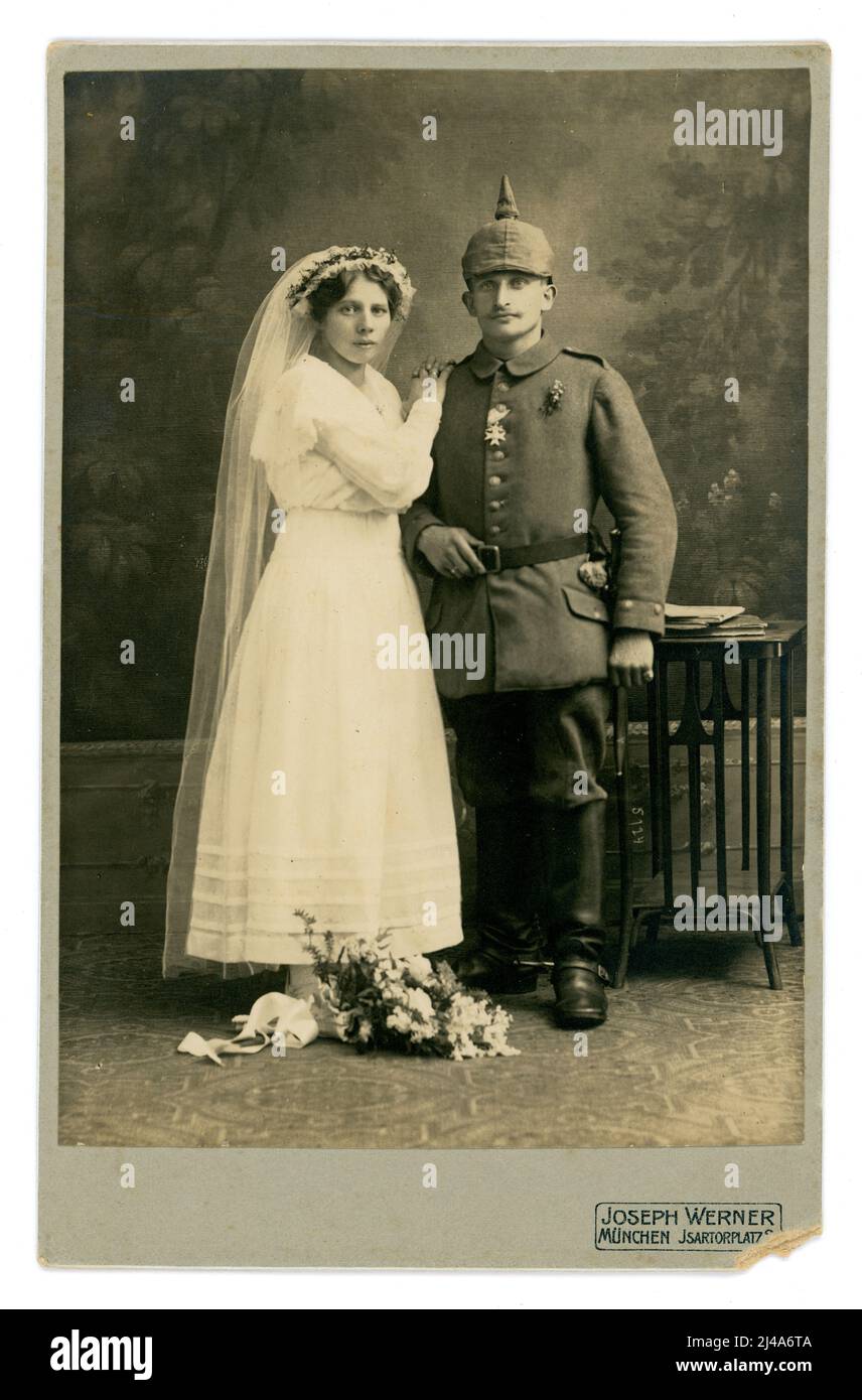 Magnifique, clair original carte de cabinet de WW1 ans studio portrait de soldat allemand bavarois de l'Empire allemand ou de l'État impérial de l'Allemagne avec son bide, il porte un 'Pickelhaube' (casque à pointes) avec une couverture Uberzug, portant des éperons sur ses bottes - cavalerie / cavalier. Il porte fièrement une croix de mérite militaire allemande bavaroise de WW1 sur son uniforme. Elle est habillée de robe de mariée blanche avec voile. Ils font un couple attrayant. Du studio photographique de Joseph Werner, à Isartorplatz Munchen (Munich) , Bavière, Allemagne. Vers 1914 Banque D'Images