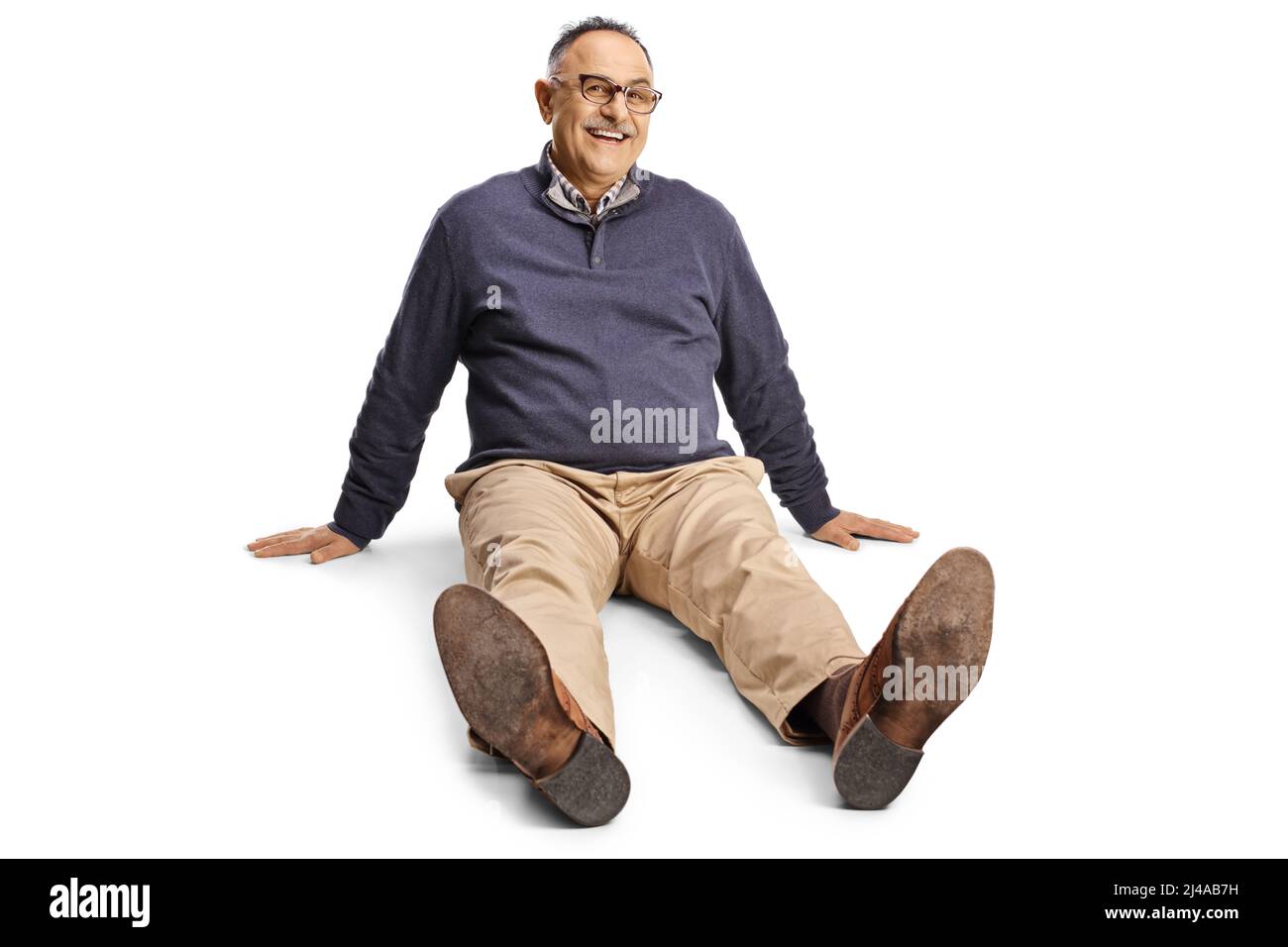 Homme mûr assis sur le sol et souriant isolé sur fond blanc Banque D'Images