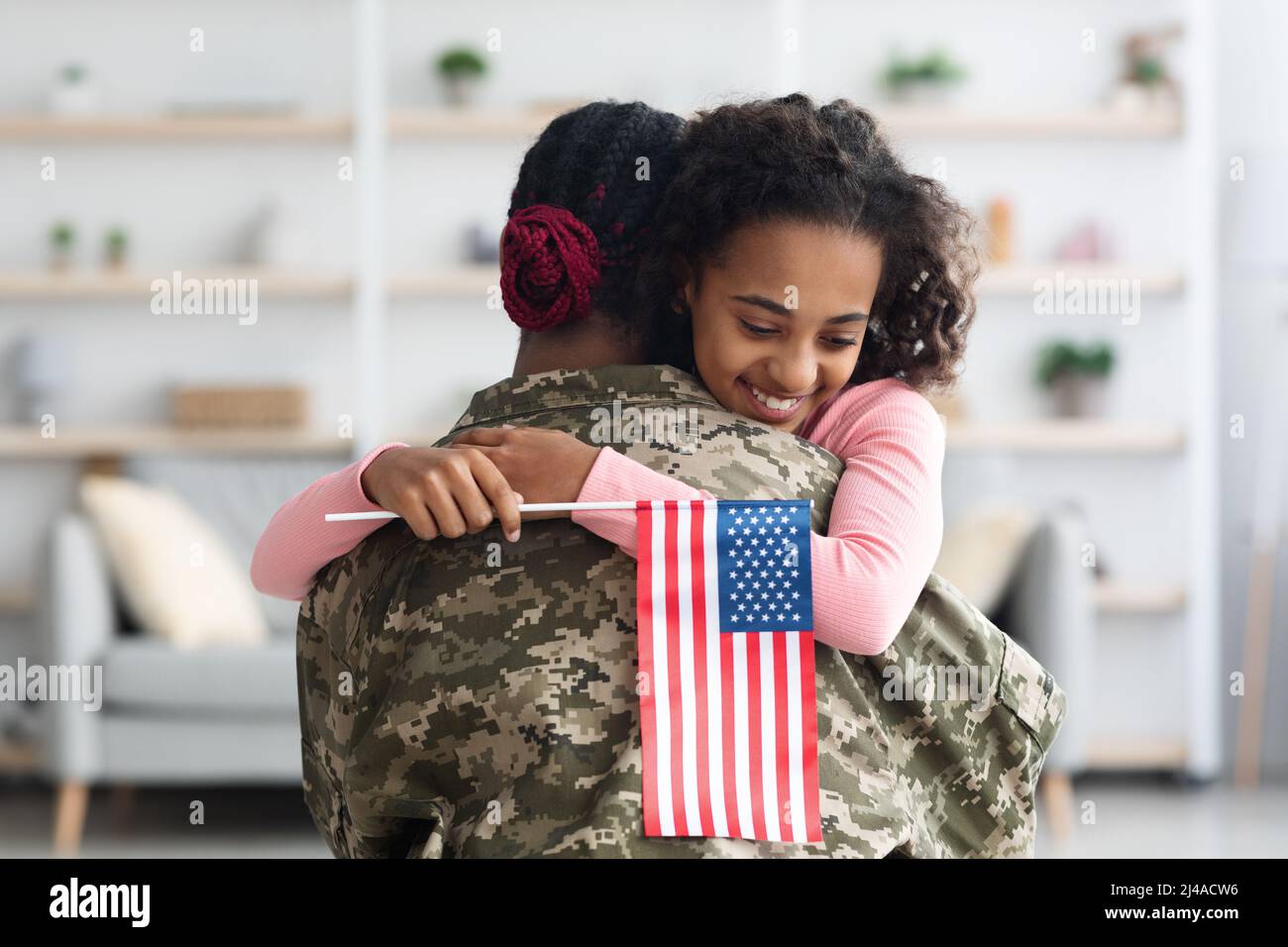 Bonne fille avec drapeau des États-Unis embrassant sa mère Banque D'Images