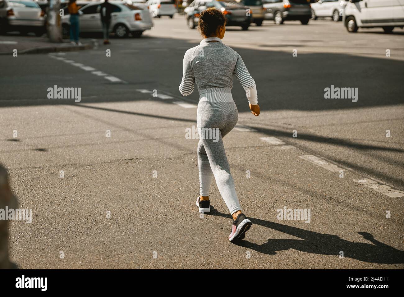 Vue arrière de la femme motivée dans les vêtements de sport gris courant dans la ville Banque D'Images