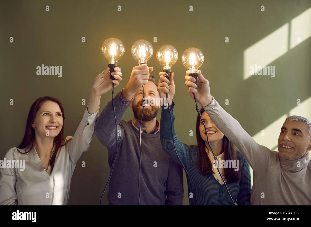 Équipe de gens heureux tenant des ampoules comme symbole d'idées créatives et innovantes Banque D'Images