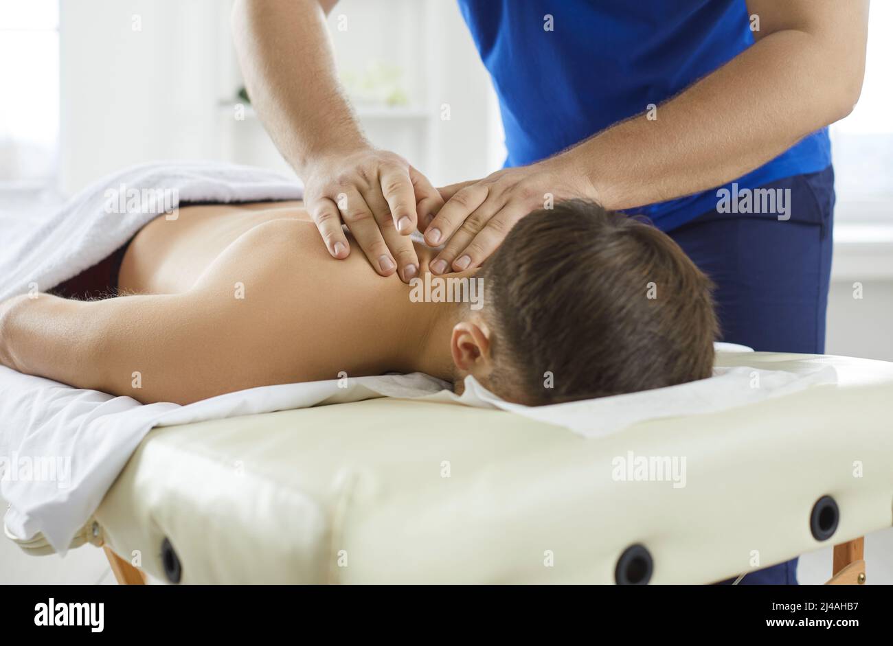 Jeune homme allongé sur une table de massage et bénéficiant d'un massage thérapeutique professionnel du cou Banque D'Images