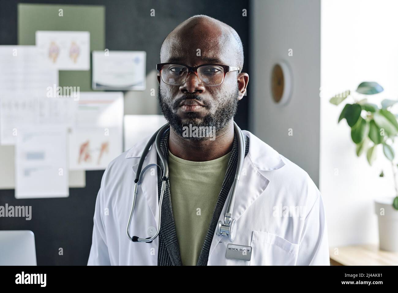 Portrait d'un homme africain médecin en lunettes et manteau blanc regardant la caméra avec une expression sérieuse Banque D'Images