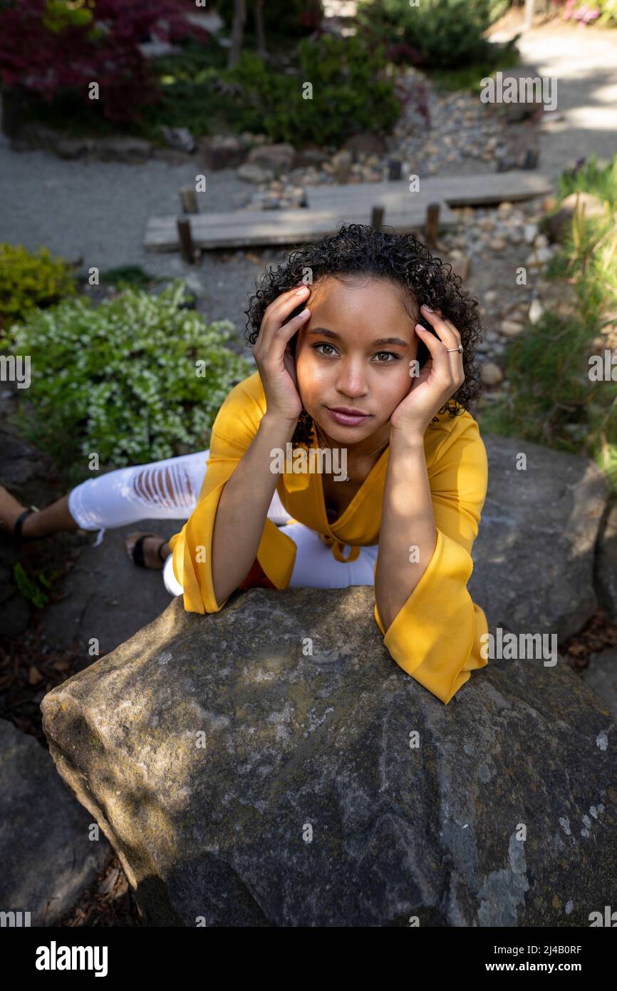 Belle jeune femme noire assise sur Rocks dans un jardin japonais Banque D'Images