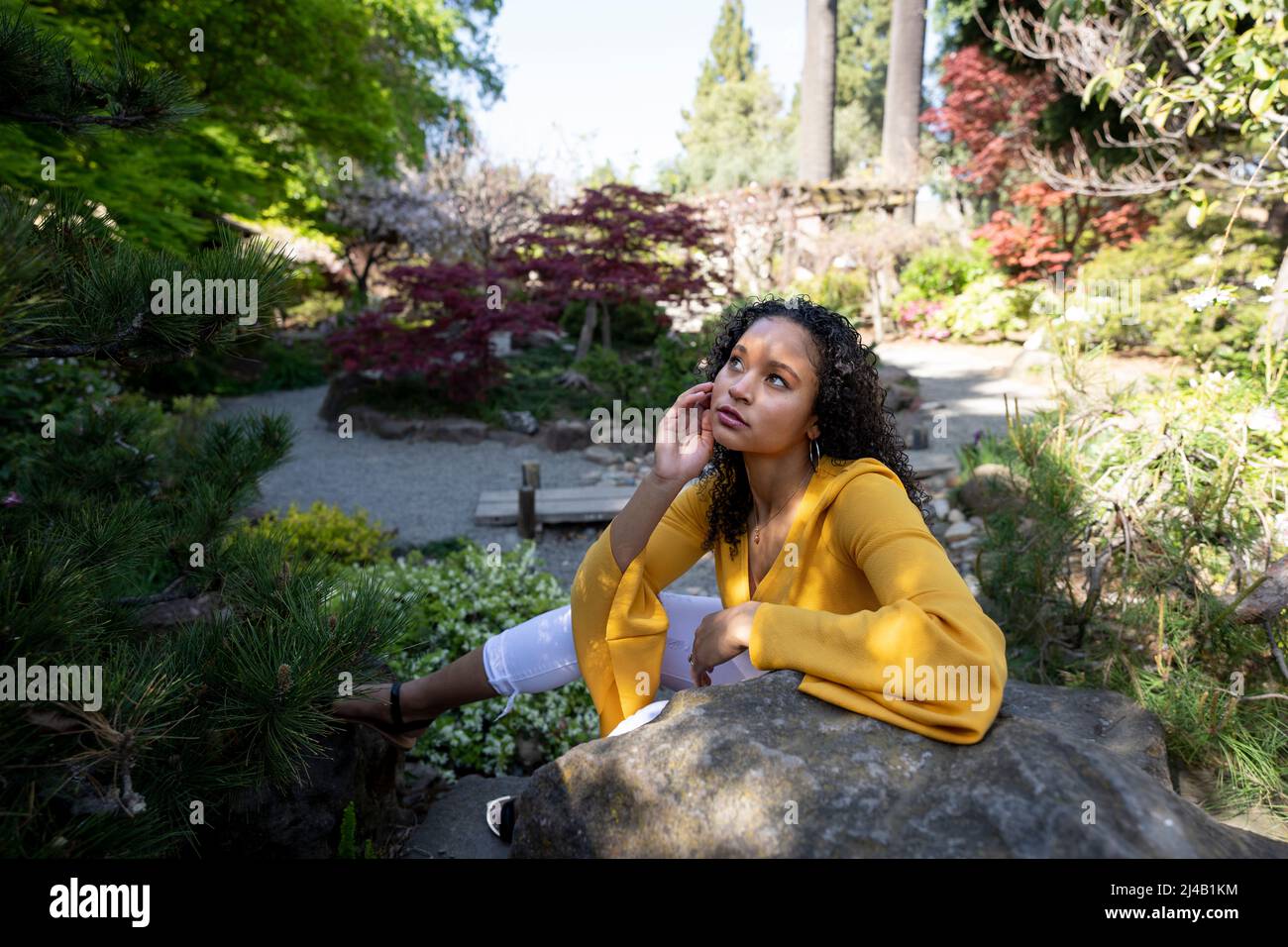 Belle jeune femme noire assise sur Rocks dans un jardin japonais Banque D'Images