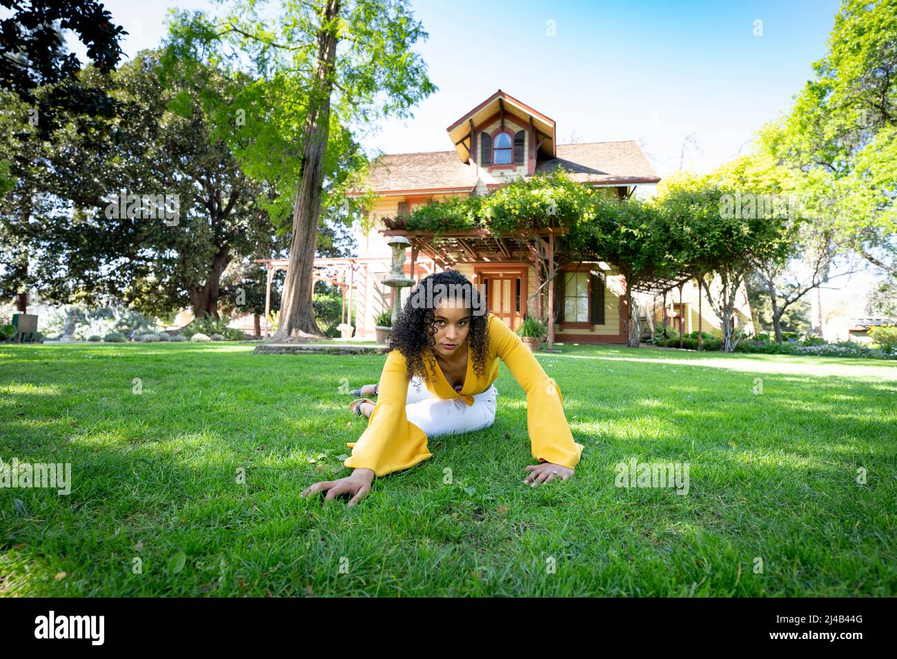 Portrait d'une jeune femme noire vibrante devant une ancienne maison victorienne Banque D'Images