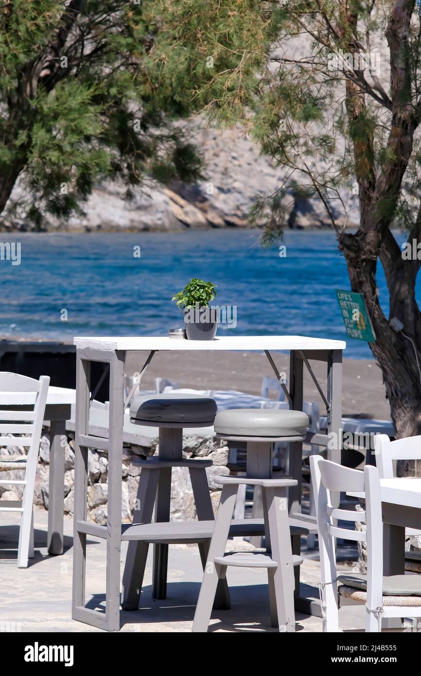 Un beau bar extérieur décoré de fleurs et offrant une vue imprenable sur la célèbre plage de Perissa à Santorin Banque D'Images