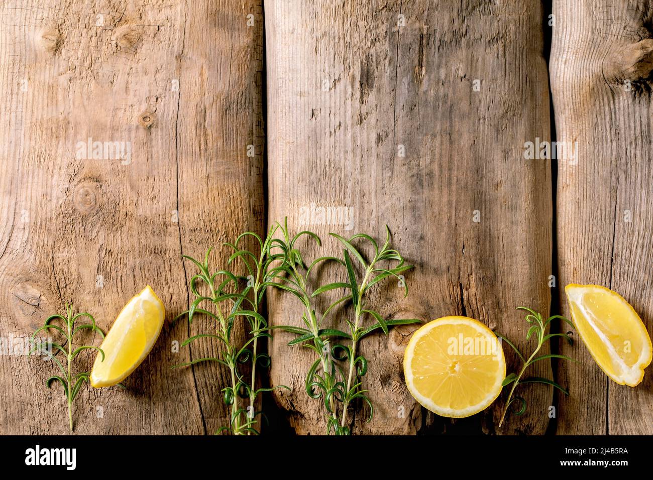 Agrumes et herbes. Des tranches de citron et de romarin frais et biologiques sont rangées sur un vieux fond en bois. Vue de dessus, espace de copie Banque D'Images