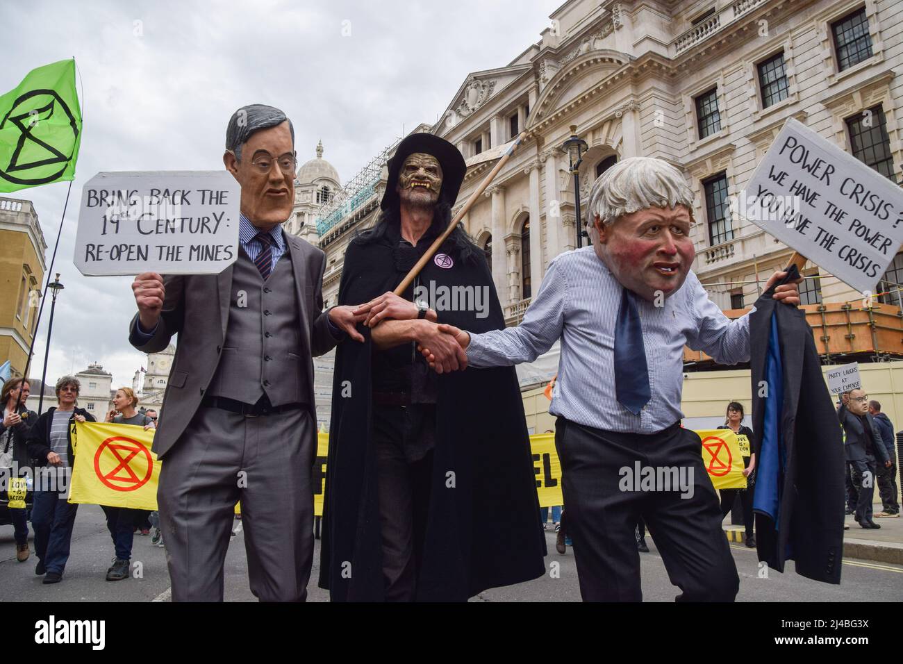 Londres, Royaume-Uni. 13th avril 2022. Les manifestants portant des masques Boris Johnson et Jacob Rees-Mogg se secouent la main avec un manifestant habillé comme le sinistre reapeur lors de la manifestation de la rébellion à Westminster. Des centaines de manifestants ont défilé dans le centre de Londres, exigeant que le gouvernement agisse sur la crise écologique et climatique. Crédit : SOPA Images Limited/Alamy Live News Banque D'Images